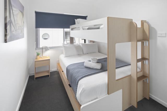 A welcoming second bedroom with a double‑and‑single bunk bed, air‑conditioning, ceiling fan and wardrobe storage, offering a practical and comfortable space for families.